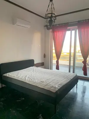 a bed in a bedroom with a large window at Traditional Apartment in Varkiza in Vari