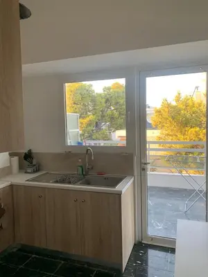 a kitchen with a sink and a large window at Traditional Apartment in Varkiza in Vari