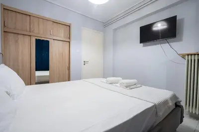 a bedroom with a white bed with a television on the wall at Petralona Hideaway - Comfort for 4 by ΜΡS in Athens