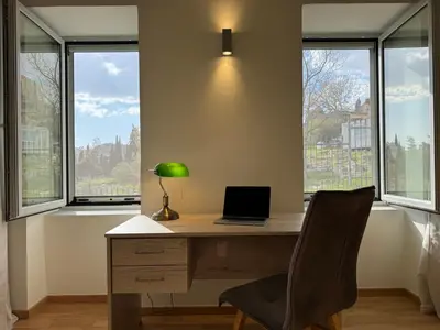 a desk with a laptop and a chair in a room with windows at East Side of Acropolis in Athens