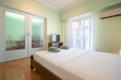 a bedroom with a large white bed and a television at Metaxourgeio Metro Apartment-Comfort for 3 by ΜΡS in Athens