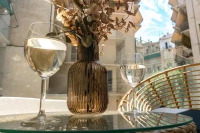 a vase with flowers on a table with two wine glasses at Skyline Spa Athens 010 in Athens
