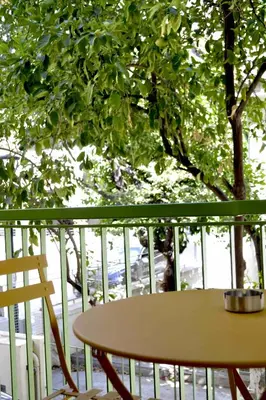 a table and chair on a balcony with a tree at Aiolos Sea loft central market Palaio Faliro in Athens