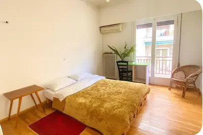 a bedroom with a bed and a table and a window at Sunny room in the heart of the city in Athens