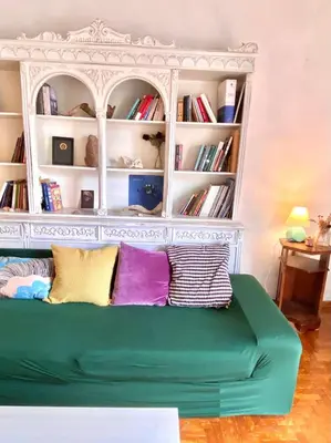a green couch in front of a book shelf at Sunny room in the heart of the city in Athens