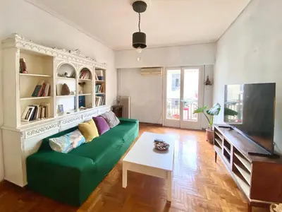a living room with a green couch and a tv at Sunny room in the heart of the city in Athens