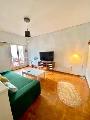 a living room with a green couch and a flat screen tv at Sunny room in the heart of the city in Athens