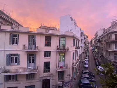 a city street at sunset with buildings and cars at Sunny room in the heart of the city in Athens