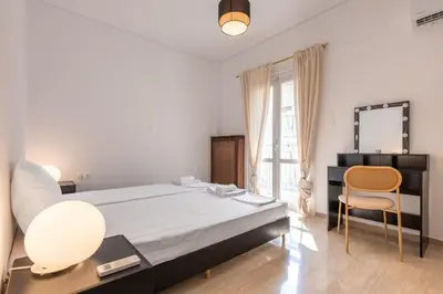 a bedroom with a bed and a desk and a mirror at Bright 2BR Apt, Athens Base Near Sea & City in Athens