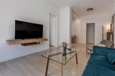 a living room with a couch and a tv on a wall at Bright 2BR Apt, Athens Base Near Sea & City in Athens