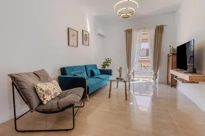 a living room with a blue couch and a tv at Bright 2BR Apt, Athens Base Near Sea & City in Athens
