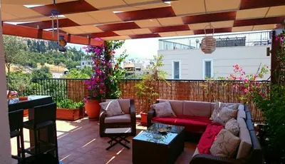 a patio with a couch and chairs and flowers at Family apartment in Acropolis with roof garden in Athens