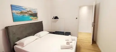 a bedroom with a white bed and a painting on the wall at Family apartment in Acropolis with roof garden in Athens