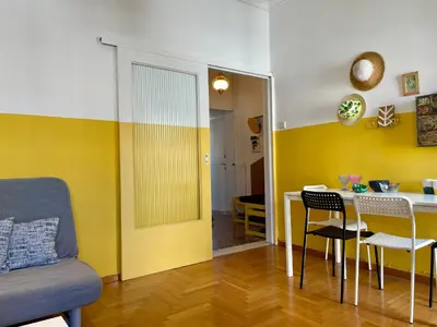 a living room with a table and a yellow wall at Acropolis Happy Place in Athens