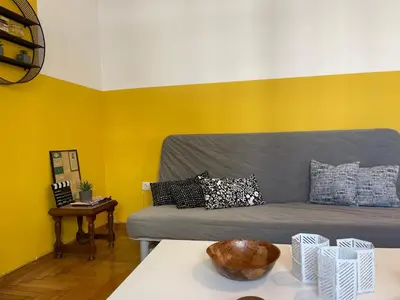 a living room with a couch with yellow walls at Acropolis Happy Place in Athens