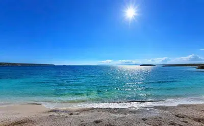 a beach with the sun shining over the water at sea soul house in Athens