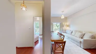a living room with a white couch and a table at Prigipos Petrou Cozy Apartment Glyfada in Athens