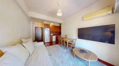 a living room with a white couch and a table at Prigipos Petrou Cozy Apartment Glyfada in Athens