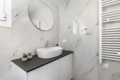 a white bathroom with a sink and a mirror at Artsi - Vibrant 3-BR Apartment & Balcony in Athens in Athens