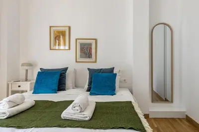 a bedroom with a large bed with blue pillows at Artsi - Vibrant 3-BR Apartment & Balcony in Athens in Athens