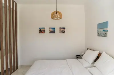 a white bedroom with a bed and a couch at One&Only apartment in Athens