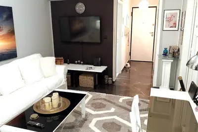 a living room with a white couch and a table at Four Seasons Cozy Apartment Paleo Faliro South Ath in Athens