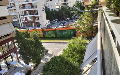 an orange and green train on a city street at Four Seasons Cozy Apartment Paleo Faliro South Ath in Athens