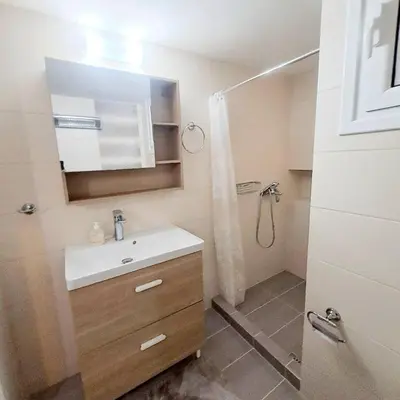 a bathroom with a sink and a shower with a mirror at Iris' Home in Piraeus