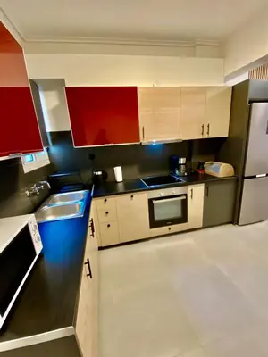 a kitchen with white and red cabinets and a refrigerator at Filolaou New Beautiful Apartment in Athens