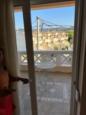 a door open to a balcony with a table and chair at Villa Clio in Porto Rafti