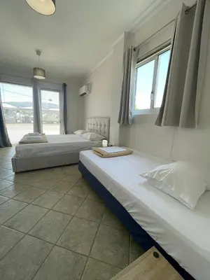 two beds in a room with two windows at RunWay Stay-24h self check in- Athens Airport in Porto Rafti