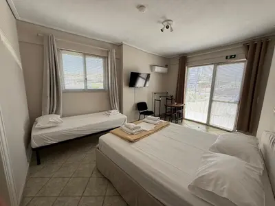 a hotel room with two beds and a window at RunWay Stay-24h self check in- Athens Airport in Porto Rafti