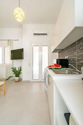 a white kitchen with a sink and a counter at Piraeus Charm in Piraeus