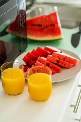 a plate of watermelon and fruit on a table with two glasses at Piraeus Charm in Piraeus