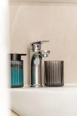 a bathroom shelf with a faucet and two cups at Piraeus Charm in Piraeus