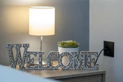 a table with a lamp and a sign that reads welcome at Ermou Central Studios and Suites! in Athens