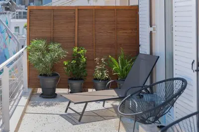 a patio with a chair and potted plants on a balcony at The HostMaster StreetMuse in Athens