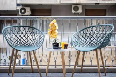 two chairs and a table with a flower on a balcony at Supreme Aprt Syntagma Kolonaki in Athens