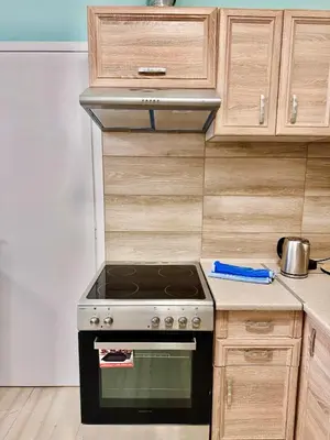a stove top oven in a kitchen with wooden cabinets at Smirni Snug Stay Garden Fits 4 in Athens