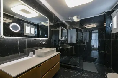 a black bathroom with a sink and a shower at Modern apartment in Glifada in Athens