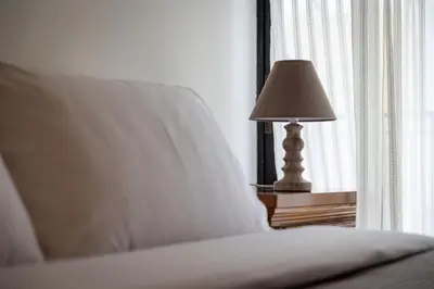 a lamp sitting on a table next to a bed at Red Arena View in Piraeus