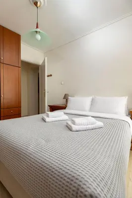 a bedroom with a large white bed with two towels at Red Arena View in Piraeus