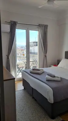 a bedroom with a bed and a large window at Palaio Faliro Breeze in Athens