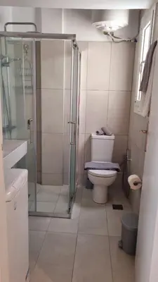 a bathroom with a toilet and a glass shower at Palaio Faliro Breeze in Athens