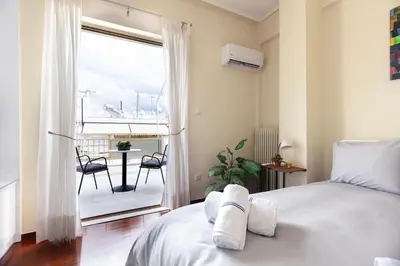 a bedroom with a bed and a balcony with a table at Pagrati Sunlit Penthouse in Athens