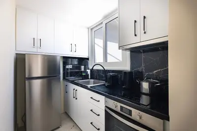 a kitchen with white cabinets and a stainless steel refrigerator at Pagrati Sunlit Penthouse in Athens