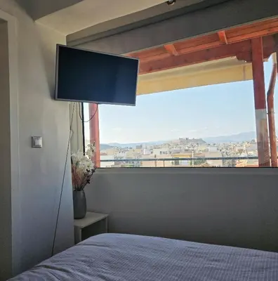 a bedroom with a large window with a bed and a television at Acropolis View Sky Suite with Jacuzzi near Metro in Athens