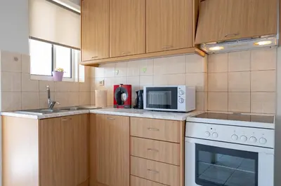 a kitchen with wooden cabinets and a white microwave at Welcome apartment in Athens
