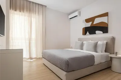 a white bedroom with a bed and a window at Glyfada Prime Living in Athens