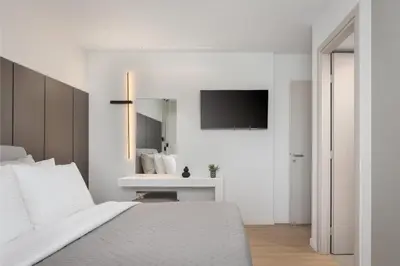 a white bedroom with a bed and a television at Glyfada Prime Living in Athens